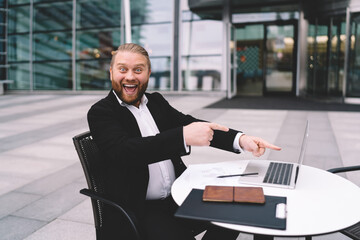 Happy businessman with laptop in city street cafe