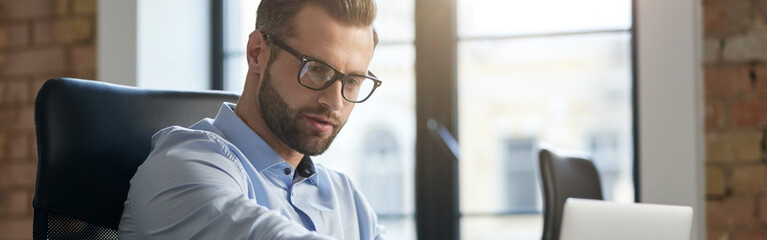 Young employee at the workplace during his working day