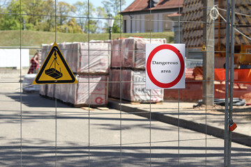 Sign with the words "Caution, danger" on the grid of a fenced object