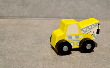 Yellow wooden toy crane truck on a white background.Children's car, Montessori eco kid toys or construction industry concept.
Selective focus.