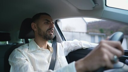 A focused Middle Eastern driver behind the wheel with a pensive expression. An Arab man driving car with care and attention. Interior shot of a young man holding steering wheel with a thoughtful look