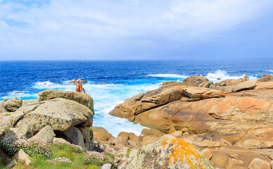Panorama view of atlantic ocean and woman sitting contempling beautiful view- Galicia, Spain