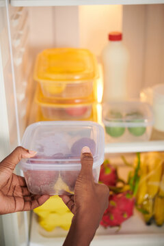 Woman organizing food storage in her fridge, putting everything into containers