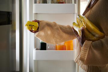 Woman taking eggs and bananas from fridge to make breakfast