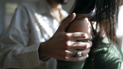Closeup hand of boyfriend consoling tearful girlfriend standing by window. Man and woman reconciliation during difficult times