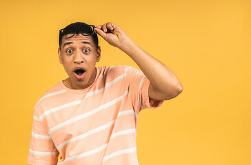 Surprised amazed shocked african american man guy in casual isolated over yellow background studio portrait. People lifestyle concept. Mock up copy space. Keeping mouth open.