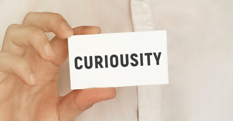 Card with text Curiousity in a man's hand