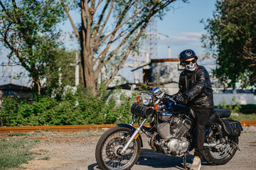 stylish male motorcyclist biker in mask and helmet with custom handmade motorcycle cruiser chopper. Stylish retro motorcycle