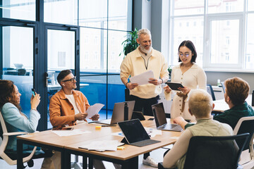 Group of professional startuppers discussing business ideas during collaborative meeting for brainstorming in office interior, successful male and female with technology talking about trade project
