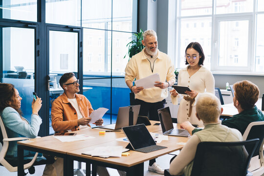 Group of professional startuppers discussing business ideas during collaborative meeting for brainstorming in office interior, successful male and female with technology talking about trade project - Powered by Adobe