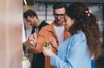 Caucasian man in optical spectacles for vision protection communicate with blurred African American woman during working process in office, diverse male and female colleagues talking at kitchenette