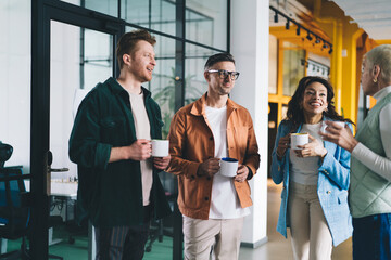 Successful male and female colleagues have business conversation during coffee break in coworking...