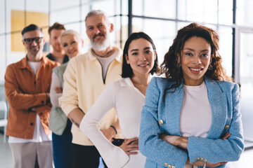 Half length portrait of African American businesswoman smiling at camera and feeling proud of successful team, cheerful female corporate director with crossed hands enjoying work time with employees