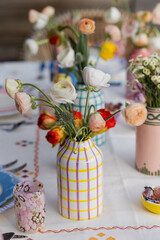 gorgeous spring flowers in colorful ceramic vases on set table at outdoor summer dinner party
