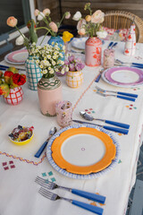 beautiful table set with colorful ceramics and fresh flowers at outdoor summer dinner party