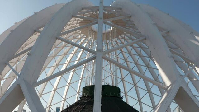 Beautiful domed structure. Stock footage. White air beams in dome structure. Top view of domed circus building on background blue sky