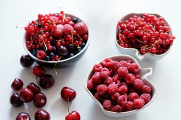 Strawberries, cherries, currant and blueberry on the white surface.