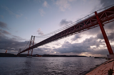 Obraz premium Beautiful landscape with suspension 25 April bridge over the Tagus river in Lisbon at night time, Portugal.