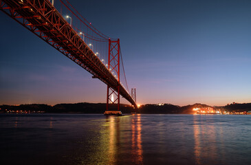 Beautiful landscape with suspension 25 April bridge over the Tagus river in Lisbon at night time, Portugal.