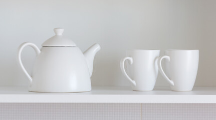 white teapot and cups on the shelf