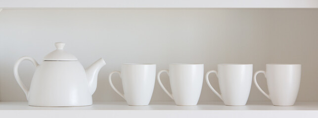 white teapot and cups on the shelf