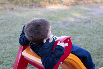 Child playing in the playground. Kid having fun sliding. Boy playing on the slide.
