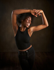 young ethnic woman with afro hairstyle dancing with raised arms