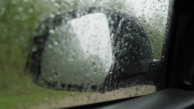 Car Mirror Behind Wet Glass