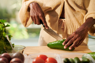 Closeup image of woman cutting avocado with sharp knife when cooking salad