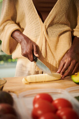 Woman cutting banana to add in porridge or muesli bowl