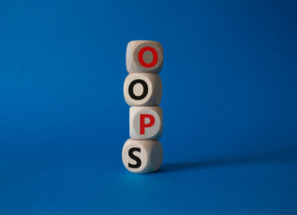 Oops symbol. Concept word Oops on wooden cubes. Beautiful blue background. Business and Oops...