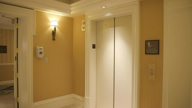 Shot of closing elevator in hallway empty corridor in luxury hotel. Modern lobby interior. Walking through a hotel hallway. Empty Corridor in a hotel. Orange Pallet. High quality 4k footage