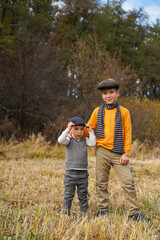 Naklejka na ściany i meble Two boys in old clothes posing in nature. Family Values. Siblings connection.