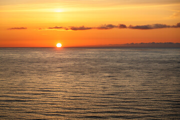 Beautiful orange sunset over the sea in the subtropics. The sun sets below the horizon line.