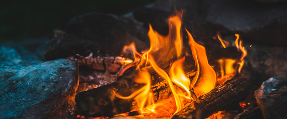 Vivid smoldered firewoods burned in fire close-up. Atmospheric warm background with orange flame of...