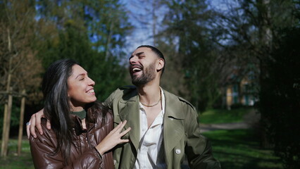 Romantic couple enjoying laughter and love in a peaceful park setting_ Authentic moment of happiness shared by happy boyfriend and girlfriend while strolling and embracing outdoors