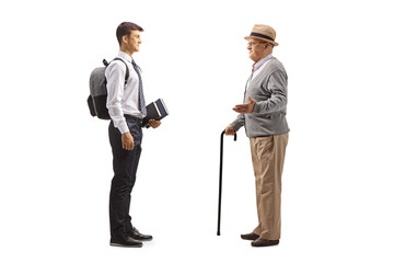 Full length profile shot of a grandfather talking to a male teenage student in a school uniform