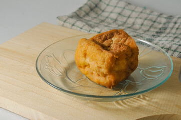 A piece of fried tofu served on a small plate and a napkin on a wooden cutting board isolated on a white background