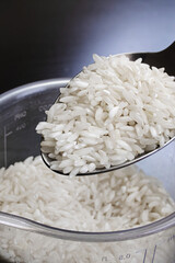 Rice grains in a spoon on wooden background
