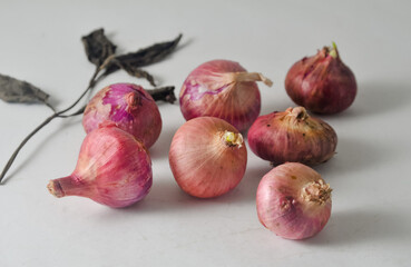 Some red onion seeds that are still intact and unpeeled with a dry leaf isolated on a white background