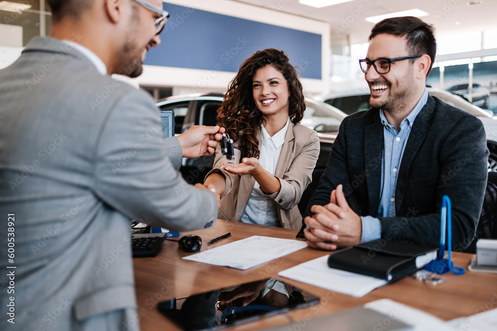 Wall mural middle age couple choosing and buying car at car showroom. car salesman helps them to make right dec