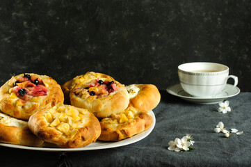 Real photo of hot homemade buns with apples and cottage cheese against a dark shabby wall. Natural light, selective focus with copy space