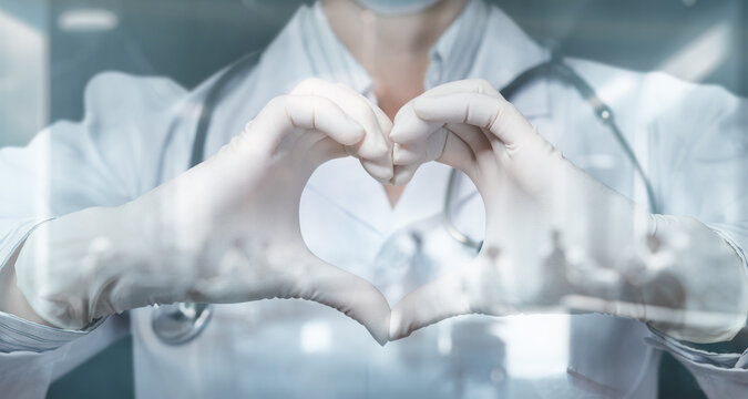 The doctor through the glass shows a heart with a gesture of hands.