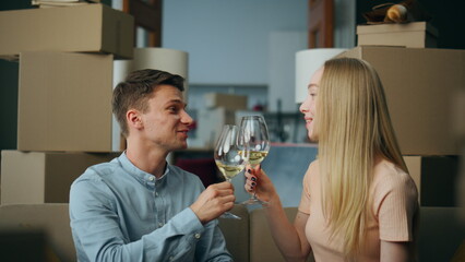 Happy couple celebrating moving into new house drinking wine near boxes close up