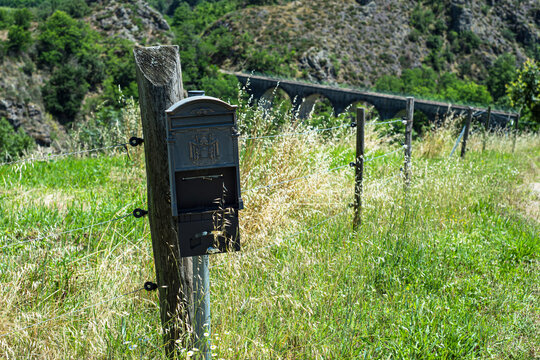 Old mailbox in the middle of nowhere in Ardeche region with the old stone railway bridge on the background.