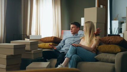 Obraz premium Couple talking new home interior discussing design sitting at comfortable couch.