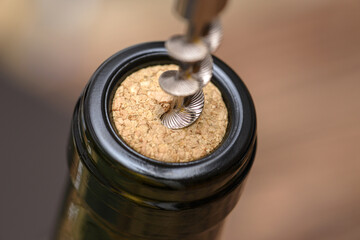 Drawing corks from bottle of wine with corkscrew