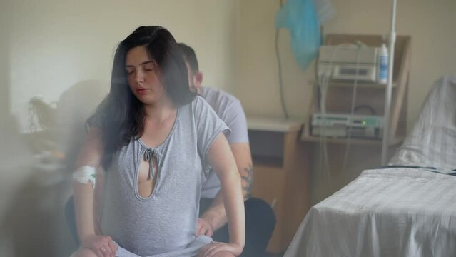Pregnant woman sitting on fit ball near husband during contractions