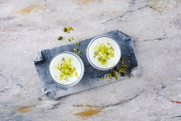 Zelfklevend Fotobehang Traditional Indian lime lassi drink with dahi yogurt, lime and chopped pistachios served as top view in a classical glass on a design plate with copy space  © HLPhoto