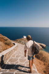 young man walking down a pretty path to the typical church of Kastro on a sunny day on the Greek island of Sifnos in the Cyclades